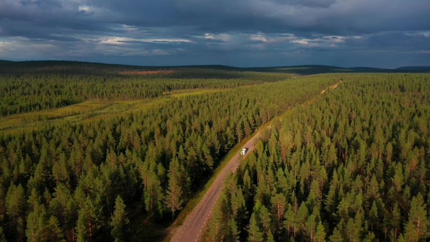 Aerial drone view following a Camper van on a arctic forest road, driving towards dark, stormy clouds Royalty-Free Stock Footage #1070334067