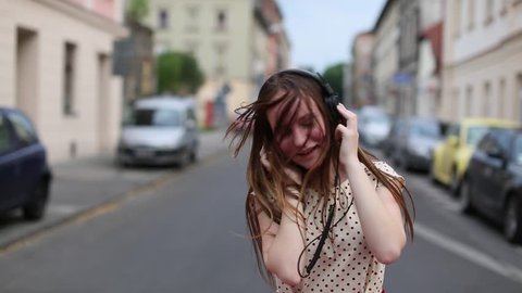 Pretty young girl listening music in headphones on a deserted street. 스톡 비디오