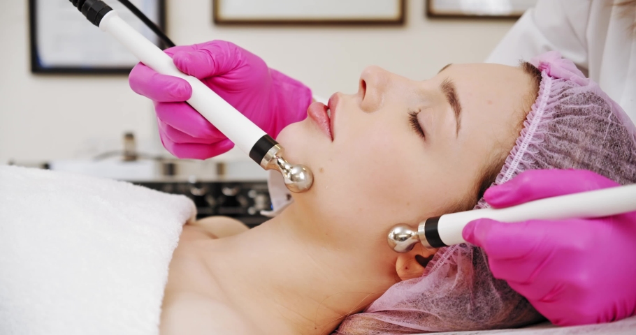 Woman in a spa salon on cosmetic procedures for facial care. Cosmetologist making a woman a therapeutic procedure on a face. Beautician makes medical procedures using a professional  equipment.
 | Shutterstock HD Video #1070339002