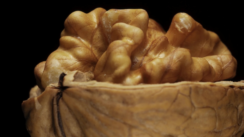 broken in half walnut on a black background rotates. Macro.