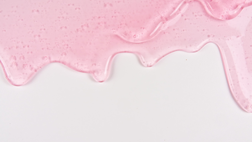 Pink Transparent Cosmetic Gel Fluid With Molecule Bubbles Flowing On The Plain White Surface. Macro Shot