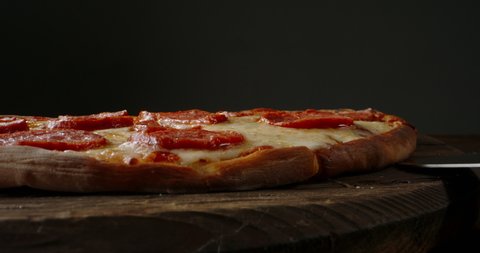 Close up shot of taking a piece of freshly baked pizza with tasty stretchy cheese. Delicious Italian pizza from the oven on black background. food and drink 4k footage