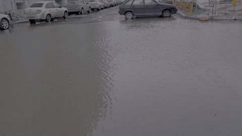 04.04.2021, Russia, Chelyabinsk: blue and red cars drives through a huge puddle. Problems of public utilities and roads. 