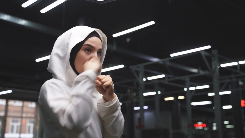 Muslim female boxer in a sports hijab is engaged in boxing, an Arab woman is doing exercises. sports in Islamic countries, concepts of women's rights | Shutterstock HD Video #1070355994