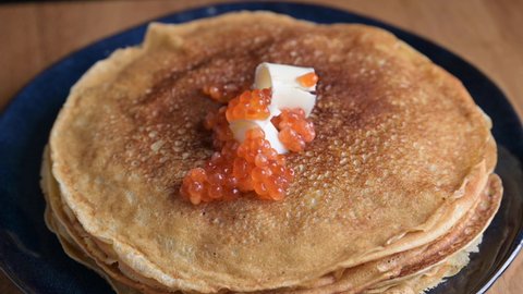 Russian thin pancakes with salmon caviar and butter. Traditional food for the holiday maslenitsa. High quality 4k footage