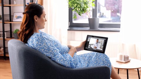 pregnancy, technology and medicine concept - happy pregnant woman with tablet pc computer having video call with doctor at home