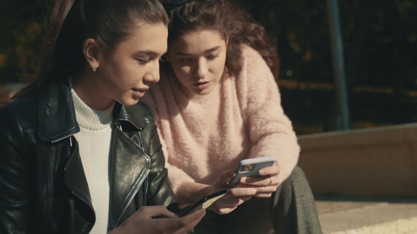 Young female friends using a smartphone outdoors