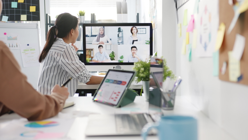 Asia businesspeople using desktop talk to colleagues discussing business brainstorm about plan in video call meeting in new normal office. Lifestyle social distancing and work after corona virus. Royalty-Free Stock Footage #1070365708