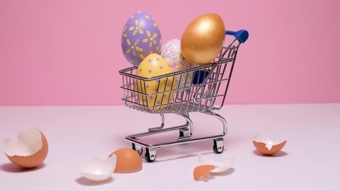Shopping cart with colorful Easter eggs. painted eggs on a pink background. Hello spring and easter concept. 4k video. Happy Easter card.