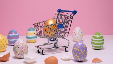 Shopping cart with colorful Easter eggs. painted eggs on a pink background. Hello spring and easter concept. 4k video. Happy Easter card.