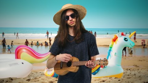 Beach Fun Summer Vacation Male Teenager Playing Ukulele. Long haired male teenager is playing ukulele during beach vacations. Medium shot