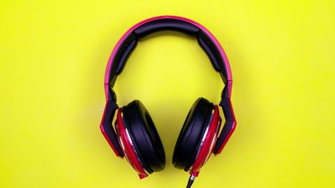 stop motion animation of red headphone on light yellow paper background Flat Lay minimal Top view Seamless loop video Time Lapse