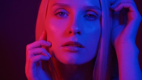 Portrait of a young woman in neon light. Colored light in the club, fashion portrait. Dressed Wear in Pink Blue Rays Light. Slow Motion