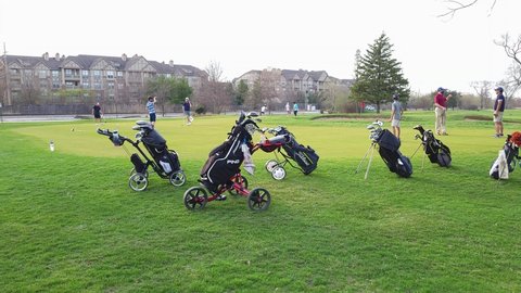 Northbrook, IL USA - April 6, 2021: Kids and adults enjoy a warm evening in early spring on a putting green at a local public golf course