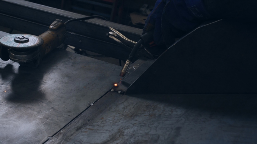 A welder in a protective mask in an auto repair shop welds a metal sheet to the bottom of the car. | Shutterstock HD Video #1070380519