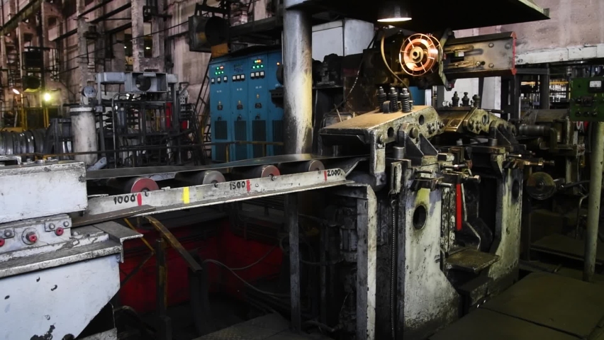 Workshop with machinery tools and equipment, rolls of steel for production metal pipes. Plant for the production of metal pipes. Stack of steel pipes.