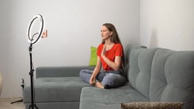 A girl blogger tells something, laughs and smiles at the mobile phone camera. The camera is mounted on a tripod, and the light from the ring lamp illuminates. A room in her house. Home. - Powered by Shutterstock - Get 15% off with code: PIKWIZARD15