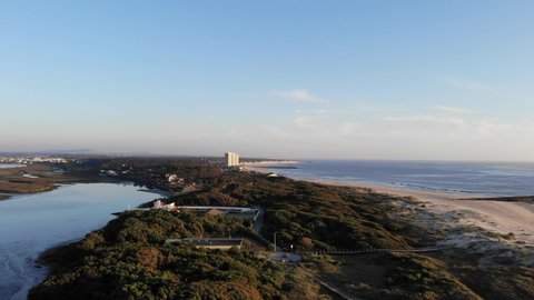 DRONE AERIAL FOOTAGE: The Northern Litoral Natural Park in Ofir, Esposende, Portugal. Wooden boardwalk and the Ofir Towers in the background. Sea, beach boulders, pebble shore and waves at sunset.