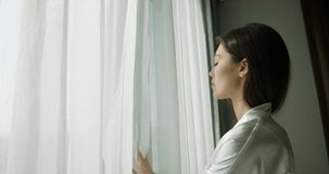 Young girl opening curtains on window in morning. Woman ready to start a new day, taking deep relaxed breath of fresh air. Millenial person feeling free on vacation 4k footage