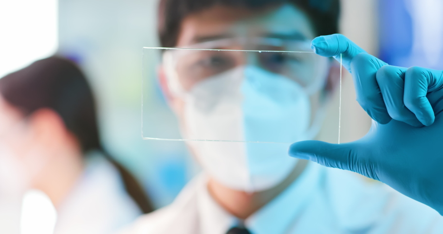 Close up of asian male scientist analyzing structure of a DNA on a transparent tablet in a modern laboratory Royalty-Free Stock Footage #1070401978