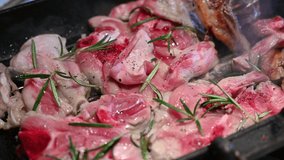 Close-up footage of a pan where the lamb has been grilled. With a fork, the cooking is checked by turning the pieces of meat. Typical dish of Mediterranean cuisine for Easter.