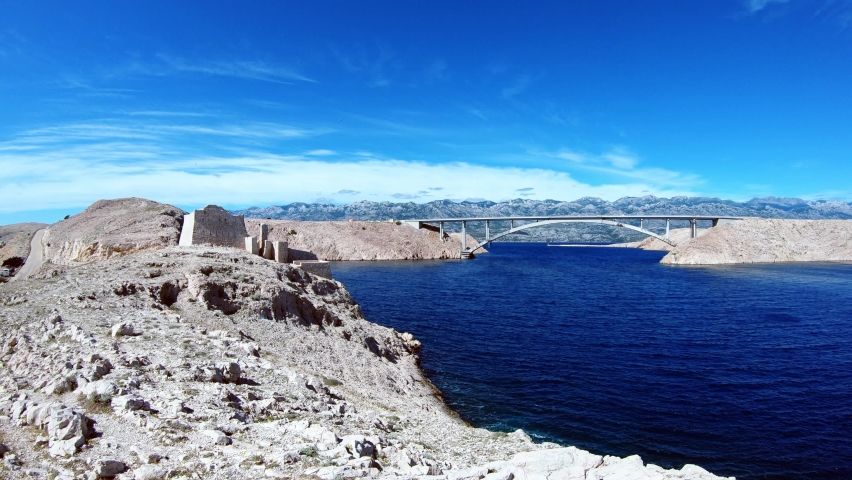 Panorama of a bridge over the beautiful blue sea and a castle ruin on the shore