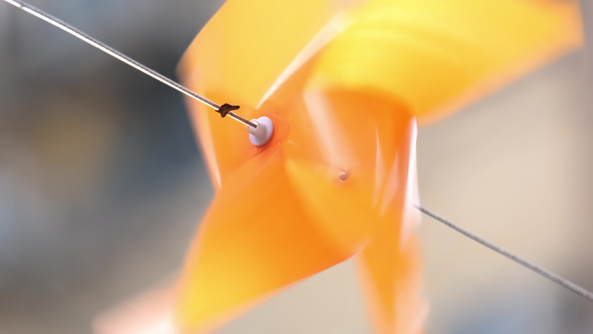 Colourful plastic pinwheel rotates with blowing wind. Slow motion.