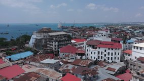 Aerial video: flies over the rooftops of houses in Africa towards the ocean and the seaport where the ship is loaded, in the frame houses, streets, coast