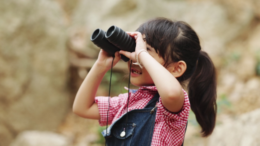 Asian Child Looking in Binocular on Meadow, Happy Tourist Little Girl Relaxing on Green Grass in Trip, Sightseeing, Landscape Seen in Spyglass, Children in Camping Learning about Nature Royalty-Free Stock Footage #1070413801