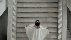 A beautiful woman in a dress with a train climbing the marble stairs. A bride in a dress with a train climbing the marble stairs. Model in the lobby of the theater. View from above. - Powered by Shutterstock - Get 15% off with code: PIKWIZARD15