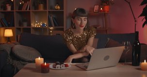 Millennial pretty woman talking while having online conversation. Fashionable young female person smiling while looking to laptop screen at home. Concept of online date.