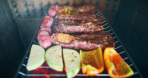 Brazilian style BBQ. Beef, sausages and vegetables being charcoal grilled on the Brazilian style grill Video Stok