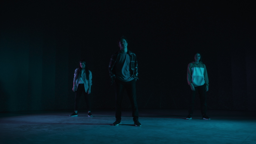 Diverse Group of Three Professional Dancers Performing a Hip Hop Dance Routine in Front of a Big Led Wall Screen with VFX Animation During a Virtual Production in Studio Environment. 105 BPM Song. | Shutterstock HD Video #1070417737