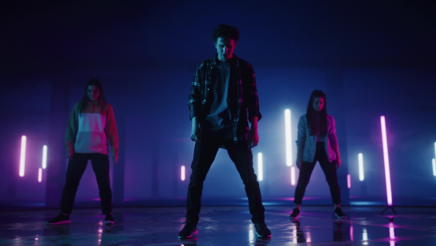Diverse Group of Three Stylish Professional Dancers Performing a Hip Hop Dance Routine in Virtual Production Studio Environment with 3D Underground Garage Space with Neon Light Lamps. | Shutterstock HD Video #1070417827