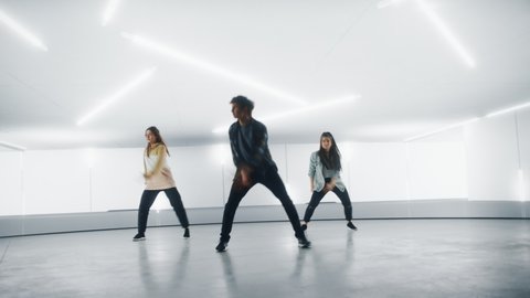Diverse Group of Three Stylish Professional Dancers Performing a Hip Hop Dance Routine in Front of Big Led Wall Screen with 3D Garage Space Created for Virtual Production in Studio Environment.