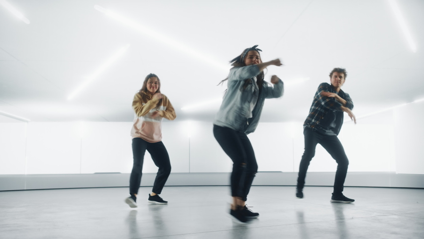 Diverse Group of Three Stylish Professional Dancers Performing a Hip Hop Dance Routine in Front of Big Led Wall Screen with 3D Garage Space Created for Virtual Production in Studio Environment. | Shutterstock HD Video #1070417851
