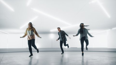 Diverse Group of Three Stylish Professional Dancers Performing a Hip Hop Dance Routine in Front of Big Led Wall Screen with 3D Garage Space Created for Virtual Production in Studio Environment.