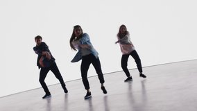 Diverse Group of Three Stylish Professional Dancers Performing a Hip Hop Dance Routine in Front of Big Led Wall Screen with Solid White Background During a Virtual Production in Studio Environment.