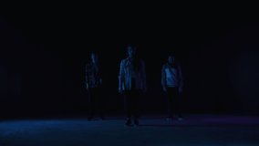 Diverse Group of Three Professional Dancers Performing a Hip Hop Dance Routine in Front of Big Led Wall Screen with Red VFX Animation During a Virtual Production in Studio Environment. 105 BPM Song.