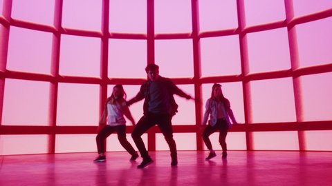 Diverse Group of Three Professional Dancers Performing a Hip Hop Dance Routine in Front of Big Led Wall Screen with Red VFX Animation During a Virtual Production in Studio Environment. 105 BPM Song.