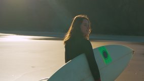 Slow motion shot camera follow beautiful authentic and real young woman in wetsuit walk with surfboard on sandy empty beach. Inspiring cinematic concept of candid female surfer - Powered by Shutterstock - Get 15% off with code: PIKWIZARD15