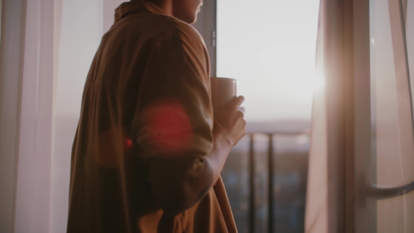 Attractive young african american woman stand on balcony looking out over city drinking a cup of tea or coffee. Relaxation, travel, interior, apartment. Slow motion | Shutterstock HD Video #1070420992