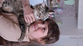 Close-up of fluffy cat in the arms of a child, tenderness and love for a pet.. Concept of happy adorable cat pets of home comfort. Shooting in slow motion. Vertical video