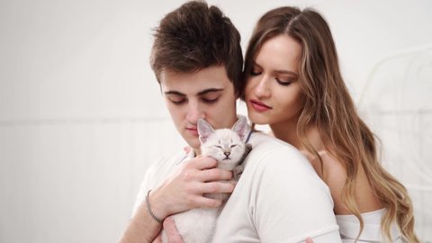A beautiful couple of young lovers holding a small white kitten. cat breed Nevsky masquerade. pet in a young family.