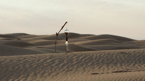 A scene in the desert. Sand spills out of the broken hourglass and is blown away by  wind. A symbol of time, life, and destiny. A hint of climate change, global warming, and environmental pollution