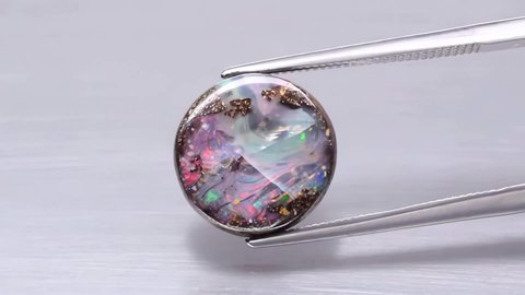 natural koroit bolder flash opal in the tweezers