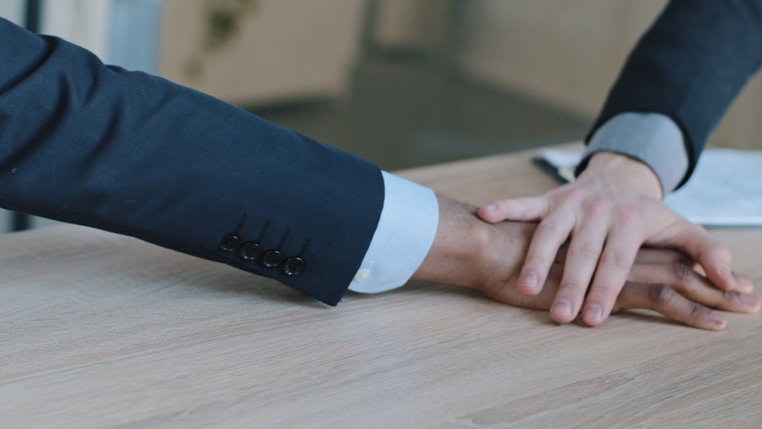 Closeup arms of multinational multiracial group company of different ethnicity people colleagues business men managers office workers stack hands put palms together on wooden table, team trust support Royalty-Free Stock Footage #1070432878