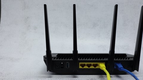 Wireless WIFI Router With Blue Patch Cord In WAN Connector And Yellow Patch Cord In LAN Connector On Office Table Background. Panning Dolly Slider Shot.