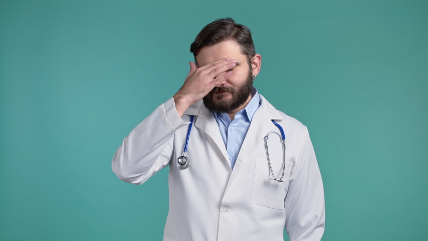 Doctor man doing facepalm gesture, like no, I forgot. Unhappy doc feeling sorrow, regret, drama, failure. He isolated on blue wall Royalty-Free Stock Footage #1070445154