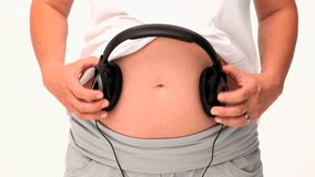 Pregnant woman letting her future baby listening to music against a white background